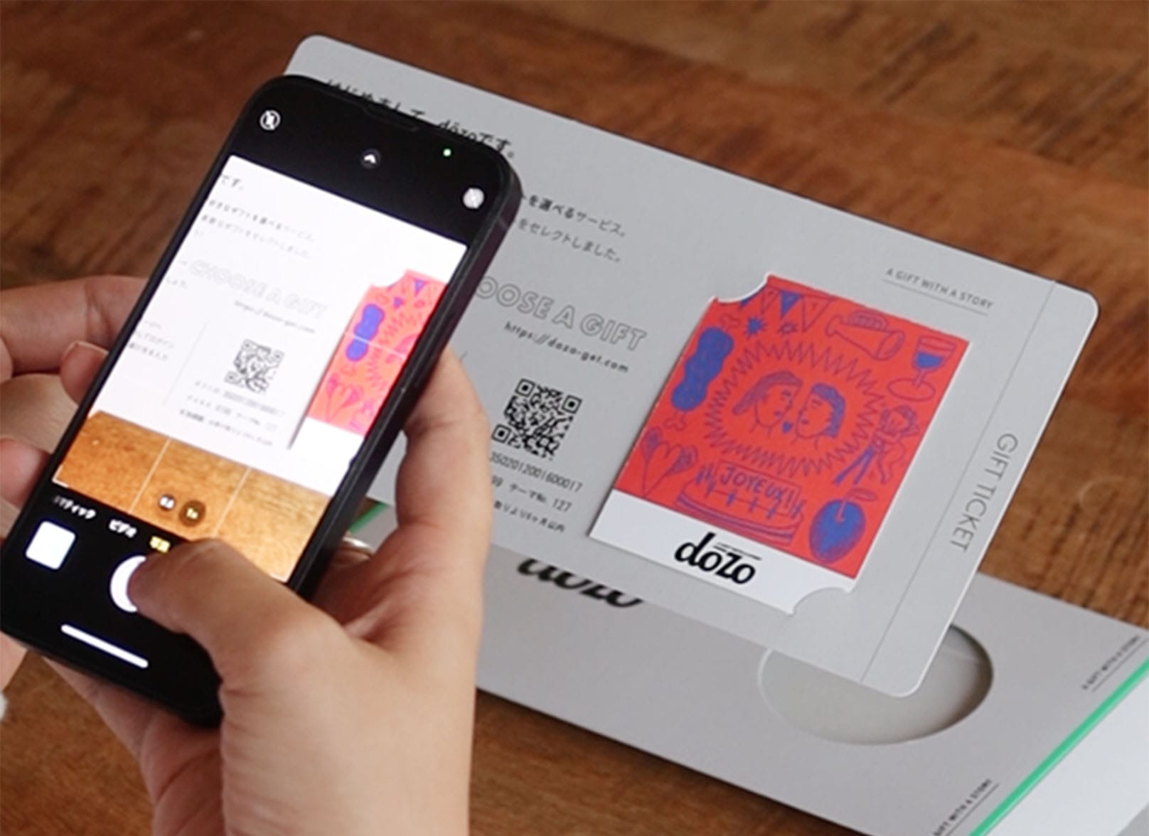도조(dōzo)의 선물 티켓을 받은 사람이 휴대폰으로 티켓 속 QR을 스캔하는 모습